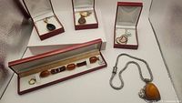 Overview of five jewelry items arranged in display boxes: four pendant necklaces and one bracelet