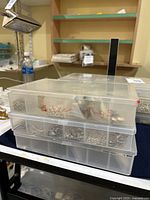 Two stacked plastic organizers with multiple compartments of sterling silver findings on table