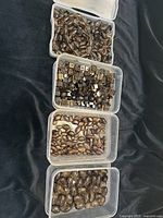 Four plastic containers holding different shapes of Smokey Quartz beads on a dark fabric background.