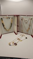 Full view of three necklaces displayed on white background with presentation cases.
