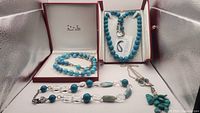 Four turquoise and shell pearl necklaces in display boxes, showing various turquoise bead styles and clear beads with sterling silver.