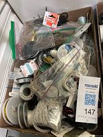 Top view of box filled with clear fishing wire, various cords, packaged bead cords, and loose wire inside a cardboard box.