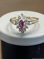 Front view of ring showing marquise-cut ruby center and diamond surround cluster