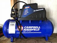 Front side view showing Campbell Hausfeld logo, pressure gauge, and air hose attached to the tank.