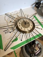 Full view of the starburst wall clock showing the metal frame and circular face with number dial.
