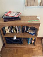 Front view of wooden shelf filled with various books and magazines on top.