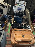 Lot includes two Canon cameras, camera cases, a manual, and new filter on a table.