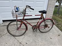 Side view of red CCM vintage bicycle with wire basket and 26-inch tires, showing overall condition and frame detail.
