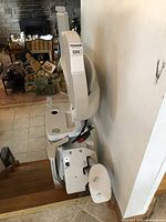 Side view of stair lift mounted on staircase showing seat folded and lowered footrest.