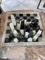 Chessboard with arranged black and white marble chess pieces on top, showing the full set and board.