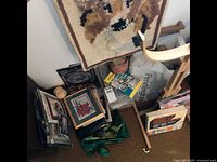 Overview of craft lot showing hooking project, framed embroidery, boxes and bags with supplies