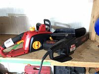 Both chain saws placed side-by-side on a wooden shelf, showing overall shape, colors, and condition.