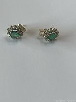 Front view of both earrings showing emerald centers and diamond halos