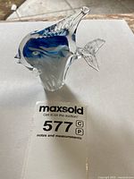 Photo of the clear glass fish sculpture showing the side profile with blue and white swirl accents.