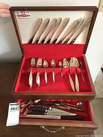 Front view of open wooden canteen showing neatly arranged flatware for 8 people with serving pieces on red lining.