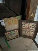Three framed items: an old document or stamp sheet, the framed 'A Decade of Dollars' coin collection, and a frame of aircraft stamps.