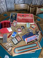 Lot overview showing Aggravation game box, cribbage board, various card decks, Jeopardy game components, and game pieces.