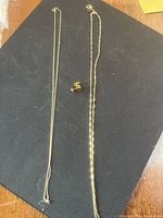 Overview of two chains and stud earrings on black background