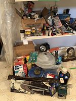 Full view of shelf with assorted hardware tools, light fixtures, cords, and boxed items.