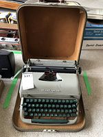 Front view of the Remington Quiet-Riter manual typewriter inside its hard-shell carrying case, showing keyboard and paper roller.