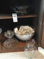 Large punch bowl placed on upper shelf inside cabinet with set pieces below