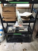 Shelf with stacked kraft paper sheets and rolled plastic sheeting with tool kits below.