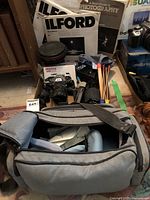 Full lot including camera bag, camera, additional lens, flash, and manuals in background