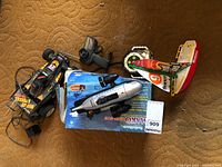 Overview photo of the radio-controlled car, remote-controlled boat in box, black radio controller, and the toy sailboat.