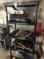 Front view of the black resin shelving unit with various tools and light bulb boxes on shelves.