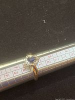 Ring on mandrel angled to show pear-shaped sapphire and diamond halo