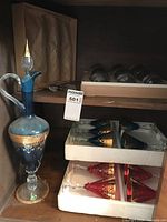 Tall blue crystal decanter with clear handle, round base, faceted stopper, gold filigree overlay