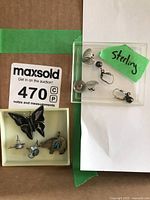 Sterling silver earrings displayed with a small assortment of animal and butterfly costume jewelry pieces, including a black butterfly pin and animal pins with turquoise accents.