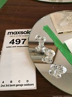 Photo showing three clear Swarovski crystal baby chick figurines on a mirrored surface, with green tape and auction tag visible.
