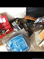 Photo showing two red metal tool boxes and multiple tools including sump pump pipe kit in plastic on the floor