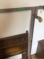 Photo showing close-up of carved detail on the wooden headboard with visible wear and attached to a bed frame.