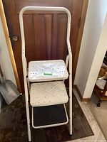 White three-step metal ladder with perforated steps and curved handle at top