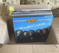 A cardboard box holding 22 vinyl records, front record is April Wine Greatest Hits