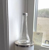 Full view of antique pressed glass shaker with metal lid and handwritten note behind it.
