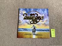 Front cover of The Beach Boys Official Tour Program book showing sunset beach scene with rider and metallic logo.