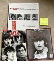 Photo showing The Beatles Recording Sessions book with black and white photos of The Beatles members on the cover, LIFE Beatles special edition magazine with black and white Beatles portraits, and Rolling Stone Special Edition magazine with George Harrison on the cover.