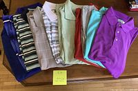 Full view of 10 folded golf shirts showing various colors and patterns from purple to stripes.