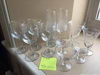Full lot of 11 assorted etched glass drinking vessels including frosted flutes and various wine glasses shown on windowsill