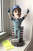 Front view of Roberto Alomar bobblehead in Toronto Blue Jays uniform with arms raised, standing on round base labeled with his name.