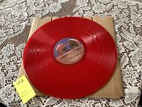 Photo of the bright red translucent vinyl record from one side showing the label and overall condition.
