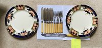 Two vintage plates and a set of knives and forks on white background