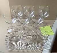 Photo showing all six clear glass wine glasses and the rectangular starburst pattern glass dish, highlighting the shape and condition of the items.