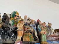 Photo showing a variety of antique statues in multiple shapes and colors, including human and animal figures grouped together.