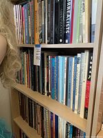 Three shelves filled with assorted used books covering multiple genres and authors.