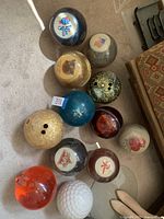 Top view of all 13 vintage bowling balls arranged on carpet floor showing various colors and personalized engravings.