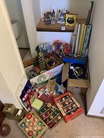 Wide view of lot showing boxes of Christmas ornaments, gift wrap rolls, village houses, and miscellaneous wrapping supplies